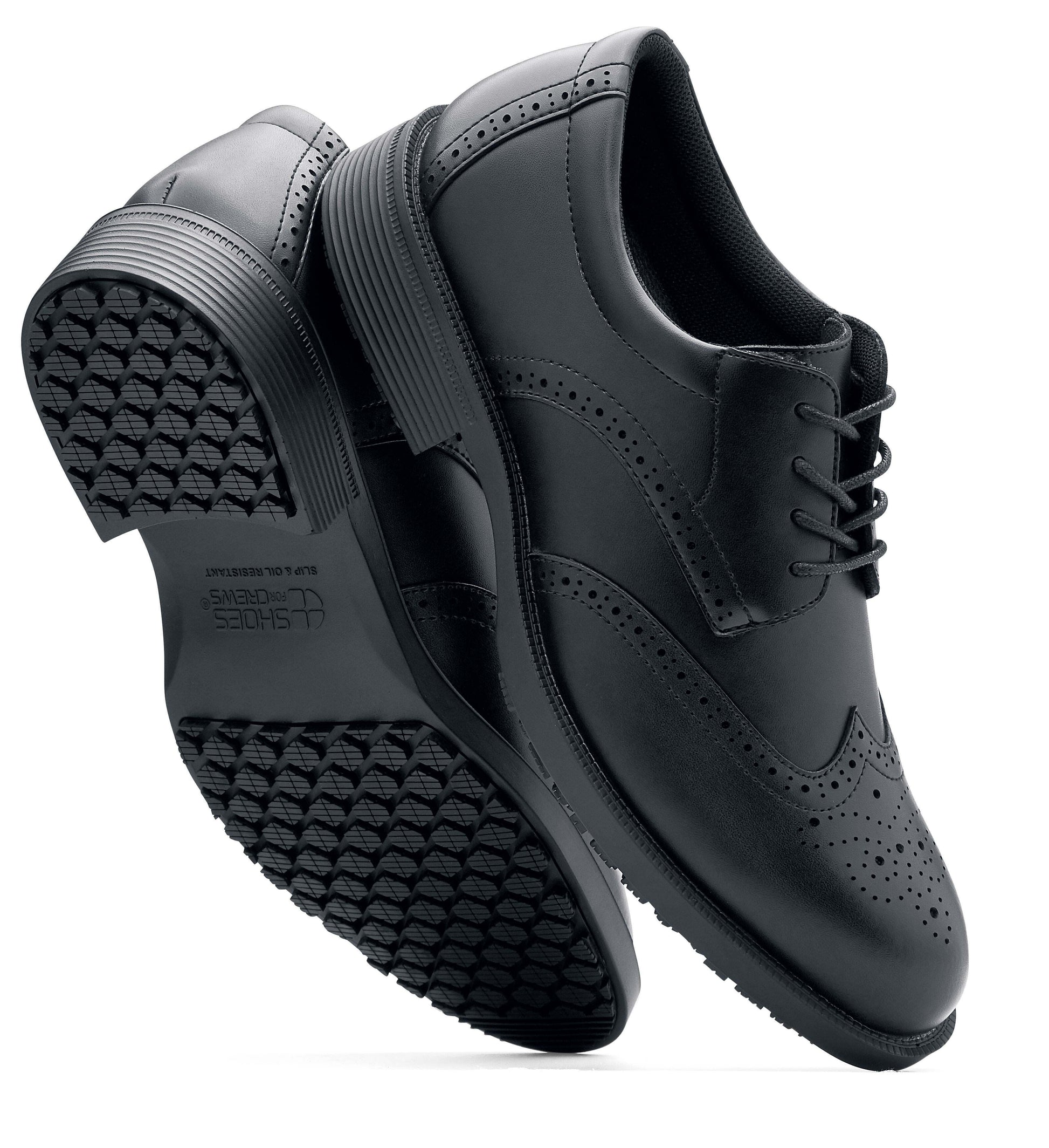 The Executive Wing Tip IV from Shoes For Crews, is an slip resistant dress shoe with a water resistant breathable leather upper to provide industry leading levels of grip and durability, viewed from the side and bottom at a vertical angle.