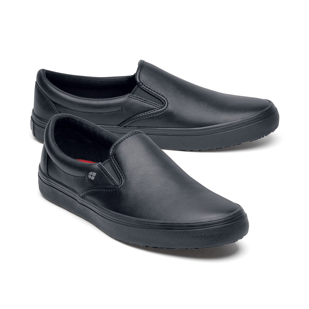 The Merlin Black from Shoes For Crews are slip-on slip resistant shoes with a lightweight design and constructed from genuine leather that has been specially treated to repel liquids from the surface, pair seen from the right side, emphasised on the tip of the right shoe.