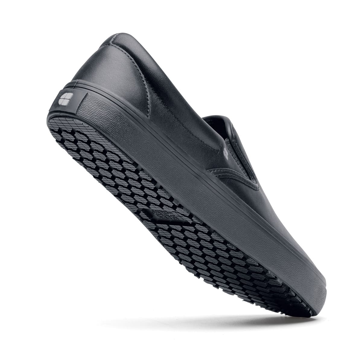 The Merlin Black from Shoes For Crews are slip-on slip resistant shoes with a lightweight design and constructed from genuine leather that has been specially treated to repel liquids from the surface, seen from the perpendicular.