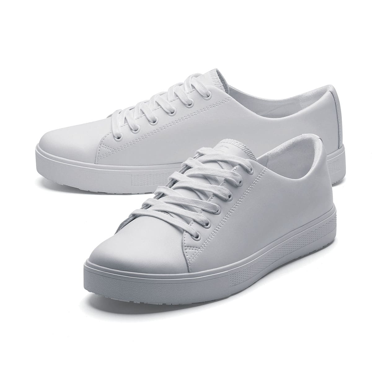 The Old School Low-Rider White from Shoes For Crews is a slip resistant lace-up designed to provide comfort throughout the day, pair seen from the left side, emphasised on the tip of the left shoe.