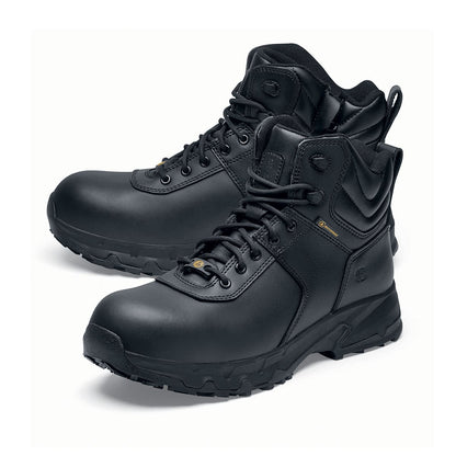 The Guard Mid from Shoes For Crews are waterproof slip-resistant safety boots with a safety toe cap, pair seen from the left side, emphasised on the tip of the left shoe.
